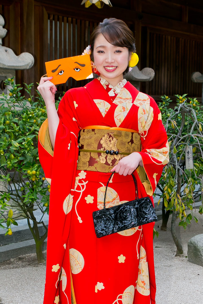 にわか面を持って微笑む着物姿の女性
